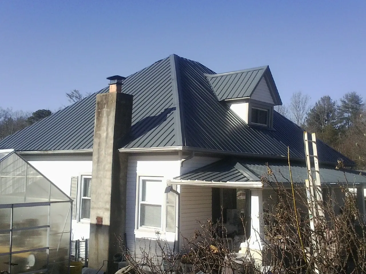 Dark blue standing seam metal roof on a white farmhouse with dormer — Slate & Tile Roof Repair by Roofing Brothers in Royal