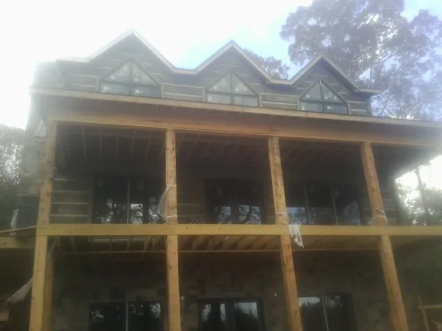 Dormers and porch framing on a large log home under construction — Roof Coating work by our crew in Royal