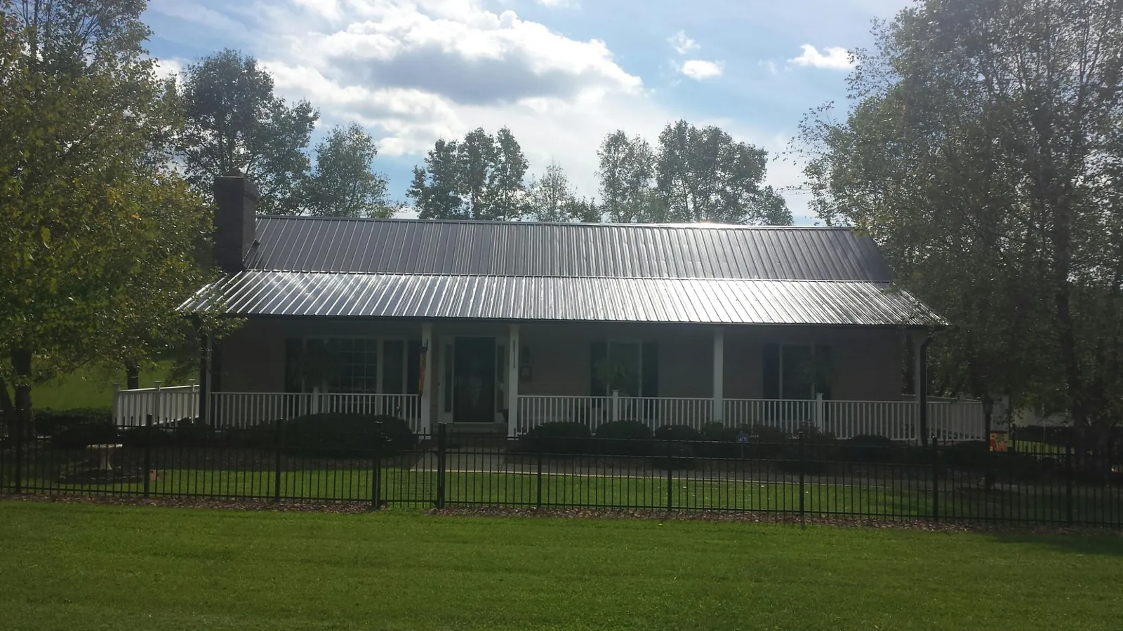 Gray metal roof on a brick ranch with a full width front porch — Gutter Guard Installation work by our crew in Royal